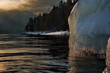 Russia. mountain Altai. Evening light in ice floods and icicles on the shore of lake Teletskoye.