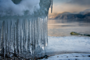 Russia. mountain Altai. Evening light in ice floods and icicles on the shore of lake Teletskoye.