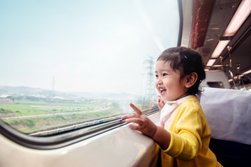 Happy and Excited Kids Traveling by Train. A Two Years old Girl Pointing her hand to Outside View,...