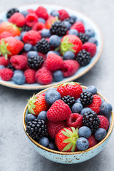 Fresh berry salad on blue dishes. Vintage wooden background.