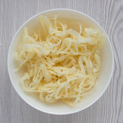 Dried squid shavings in a white Cup close-up on a light wooden background © Людмила Ильина