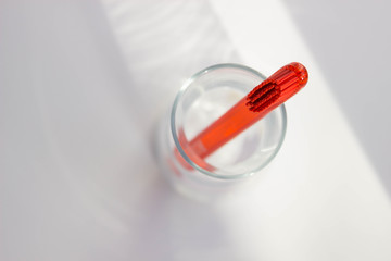 Red style toothbrushes in glass on table on light moning background, top view