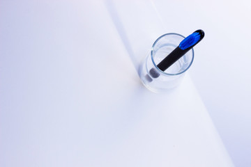 Black style toothbrushes  wiht blue bristle in glass on table on lwhite moning background