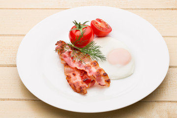 Fried eggs with bacon on the wooden table.