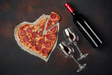 Heart shaped pizza with mozzarella, sausagered and wine bottle. Valentines day greeting card on...