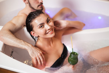 smiling Asian lady enjoying having tube with loving guy. chromotherapy concept. pure bliss