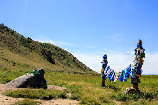 Colorful buddhist prayer flags hadags on ritual shamanic poles near the Buha Shuluun which translated from buryat as Bull Stone. Buddhist serges near Buryat village Suvo, Republic Buryatia, Russia