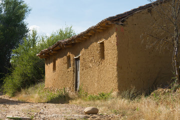 Vista lateral de antigua y sencilla casa de zona rural construida en adobe © Siur
