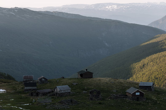 Rural cabins overlooking a mountain valley in Norway during sunset