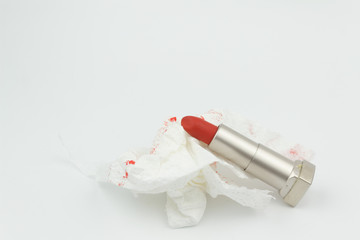 Red lipstick with tissue with red lipstick stain on isolated white background