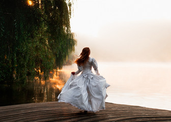 The fairy near water.  Girl in white dress on lake. Woman on a wooden bridge. Fantastic big lake....