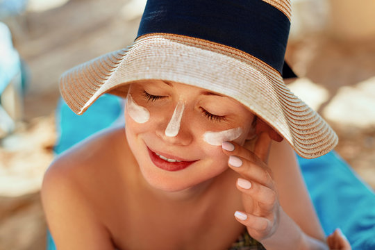 Facial Care. Female Applying Sun Cream and Smiling. Beauty Face.  Portrait Of Young Woman in hat Smear  Moisturizing Lotion on Skin. SkinCare