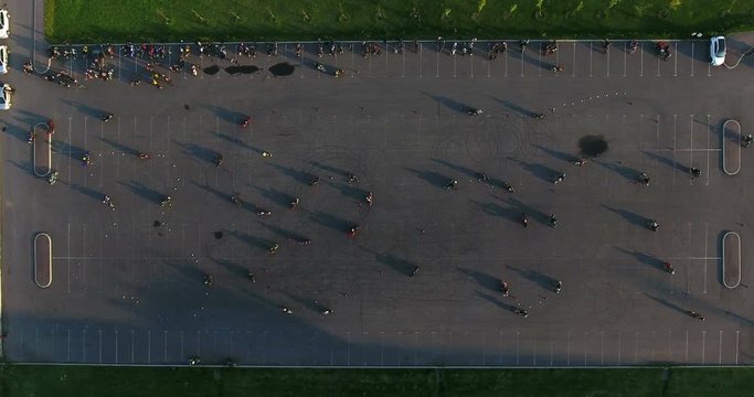 Top view at motorbikes riding through cones and entering curves, wave racing on urban asphalt square