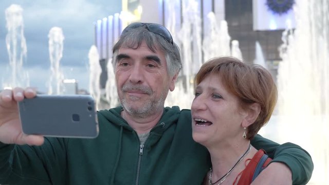 Romantic mature couple taking selfie - Fountain in Background
