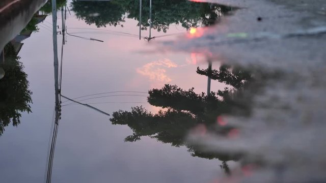 reflection twilight sunset sky in puddle water flooding on street