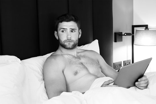 Handsome,  Naked Male With Beard Using  Ipad Tablet In Bed