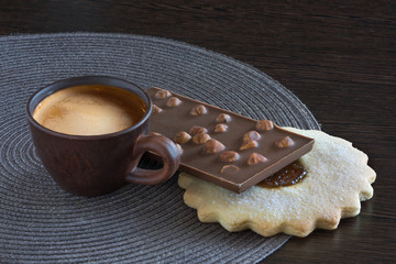 Cup of coffee, cookies, chocolate on the tray of wooden table.