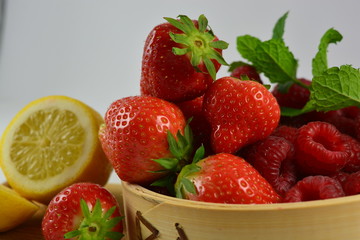 Fototapeta na wymiar Strawberries, raspberries and a lemon on a white background