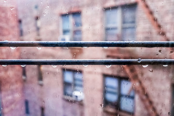 Small apartment window in New York City NYC urban Bronx, Brooklyn brick housing, guard rail, security bars, grunge poverty, wet raining, rain drops, droplets hanging