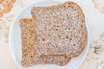 Closeup of two slices pieces of whole wheat sprouted toasted grain bread on plate, plain simple on table macro flat top down view