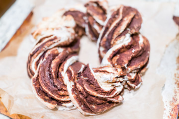 Closeup of golden red orange baked whole cinnamon roll swirl twist spiral cake bread on parchment paper tray for festive traditional holiday