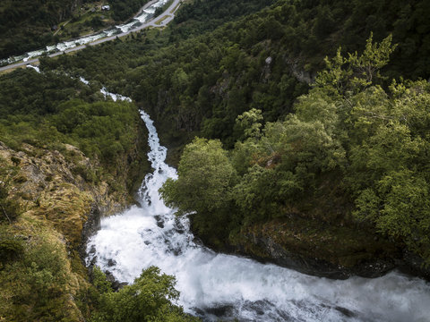 Aerial of a roaring powerful waterfall through a forest fjord valley in Norway