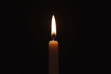 Wax candle burning on black background, closeup