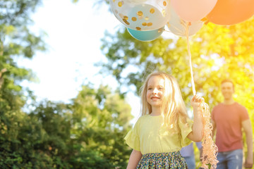Cute little girl with colorful balloons outdoors on sunny day