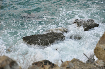 Waves crashing on the rocks in the blue ocean. Seascape of the storm and the stones. Big splash at the coast. Sea breaking