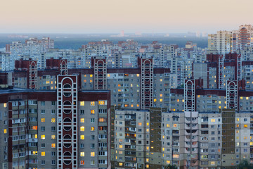 Urban view of many apartment buildings at dusk with lights switched on inside. Densely populated residential district of Troieshchyna, neighborhood of Kiev, Ukraine