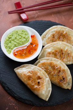 Close-up of pan fried korean potstickers served with dipping sauces, vertical shot, selective focus