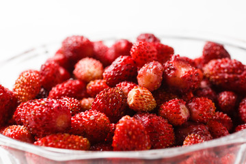 Fresh strawberry fruit in a glass dish on a white background. Close up.