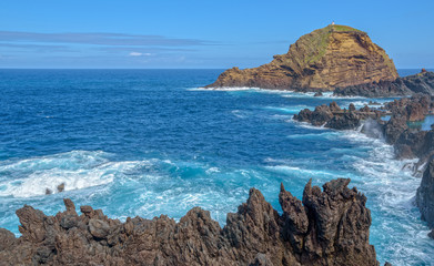 Fototapeta na wymiar Porto Moniz. The automated Lighthouse in front is situated on the top of 'Ilheu Mole'. Madeira Island, Portugal.