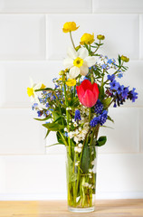 spring bouquet of wild flowers in a glass on a white background. House interior