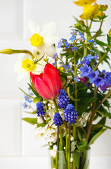 spring bouquet of wild flowers in a glass on a white background. House interior