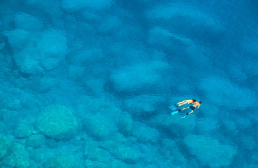 Fototapeta na wymiar Unidentifiable couple swimming in the Mediterranean Sea in Greece near the island of Lefkas