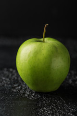 Green apple on dark stone background