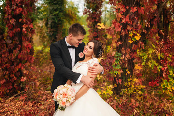 Cute newlyweds couple spend time together in an autumn forest