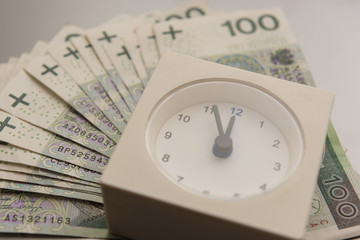 Close-up of clock and money with silver background, stack of Polish Zloty banknotes (PLN)