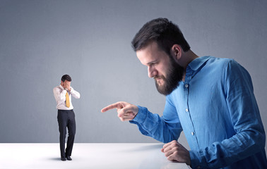 Young professional businessman being angry with an other miniature businessman 