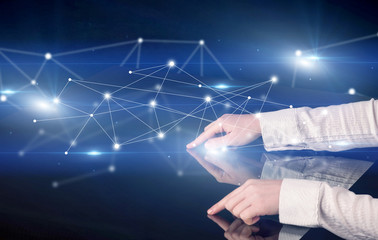 Male hands touching interactive table with blue connectivity graphic in the background