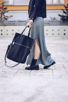 street style portrait of an attractive woman wearing a long dress, biker ankle boots and a big black leather tote bag . fashion outfit 