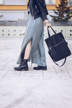 street style portrait of an attractive woman wearing a long dress, biker ankle boots and a big black leather tote bag . fashion outfit 