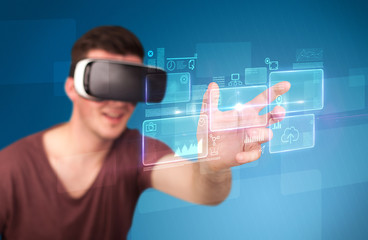 Young impressed man wearing virtual reality goggles with blue squares containing data at his fingers 