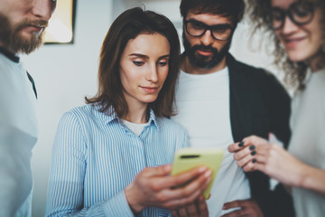 Coworkers business meeting concept.Young women holding mobile smartphone hand and showing information to her colleagues. Cropped.