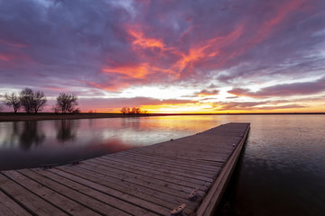 Sunrise or sunset on the fishing dock with colorful clouds reflecting in the lake