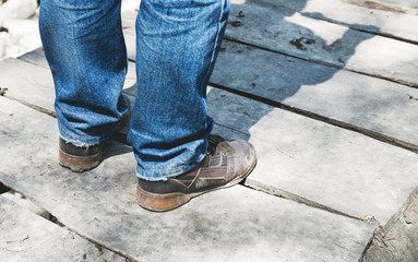 Close-up of male legs in dirt sneakers on a wooden bridge