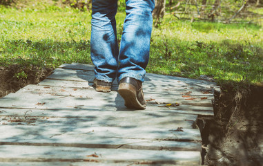 Close-up of male legs in dirt sneakers on a wooden bridge