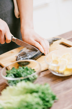Woman cutting raw fish in the kitchen.