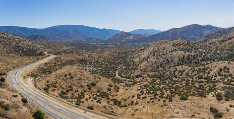 Panorama of vast desert wilderness and curving highway road through the emptiness.